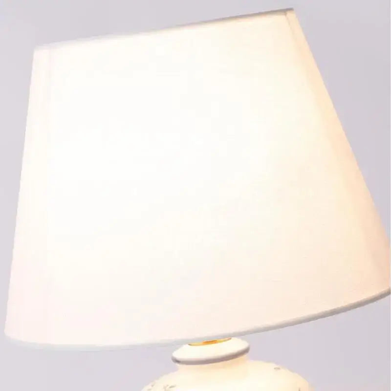 Cream-colored fabric lampshade with a soft tapered design on a classic white and black porcelain table lamp for living room decor