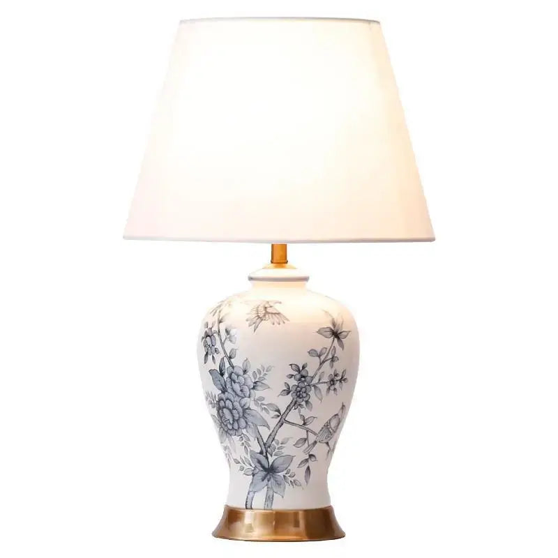 Classic white porcelain table lamp with blue floral bird motifs and gold-toned base for living room decor