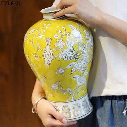 A vibrant yellow ceramic vase with white floral and bird motifs, gold-trimmed rim, for decorbites blue white porcelain decor