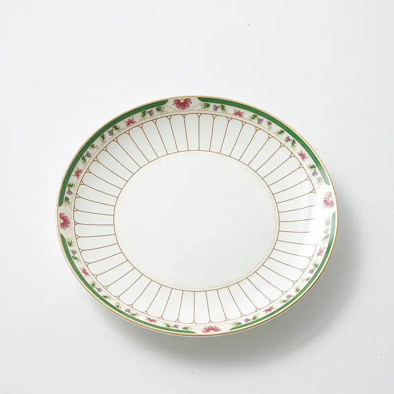 White ceramic plate with green border and floral motifs paired with classical gold-striped ceramic cup and saucer set