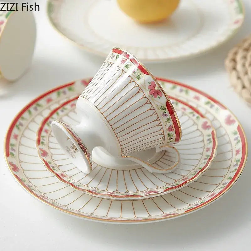Delicate white porcelain ceramic cup with pink floral motifs and gold trim in classical gold-striped saucer set
