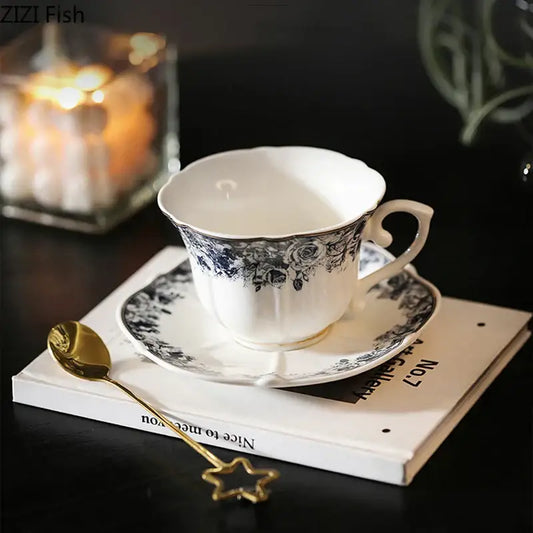 White porcelain ceramic cup and saucer set with delicate black floral pattern and gold trim in classical grey blue rose style