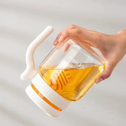 Transparent glass tumbler 1000ml with white plastic handle and lid filled with golden amber honey by decorbites