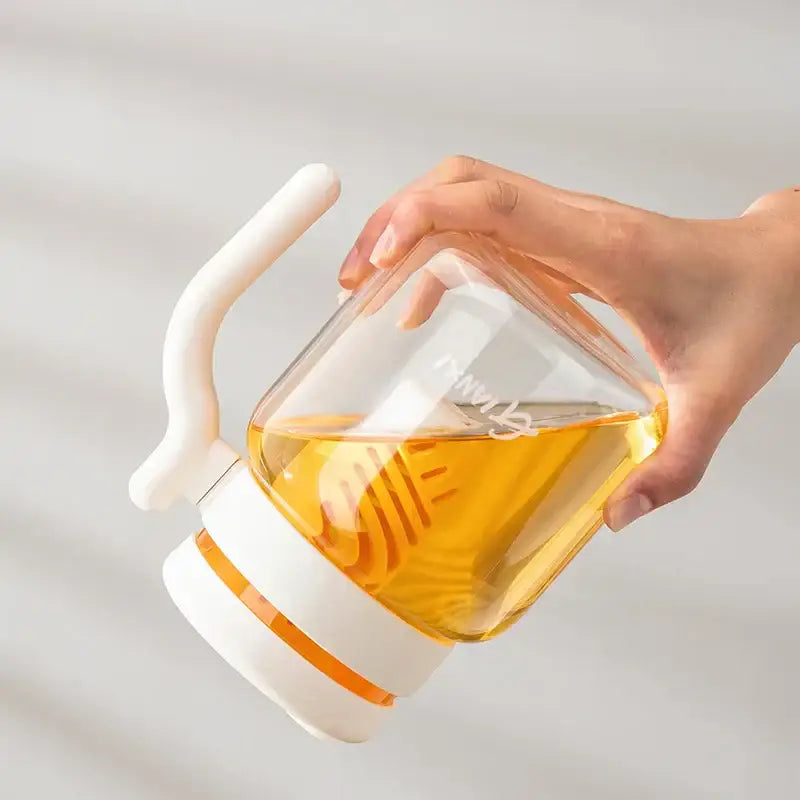 Transparent glass tumbler 1000ml with white plastic handle and lid filled with golden amber honey by decorbites