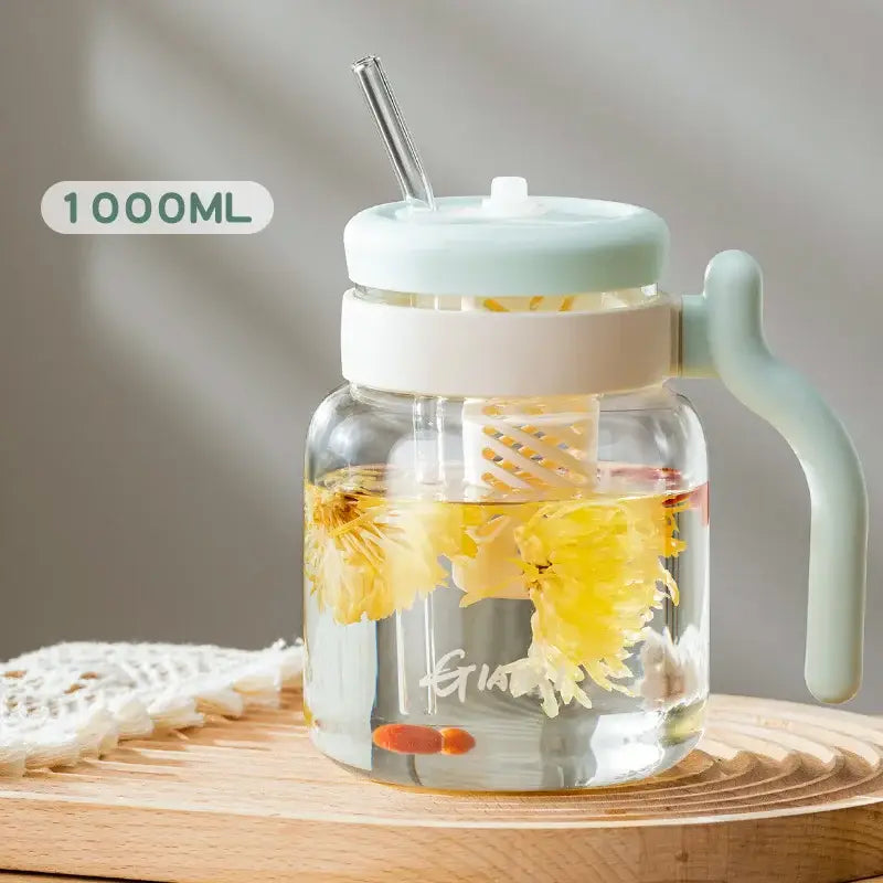 Clear 1000ml glass tumbler with handle and straw featuring a light mint green lid and yellow flowers in water