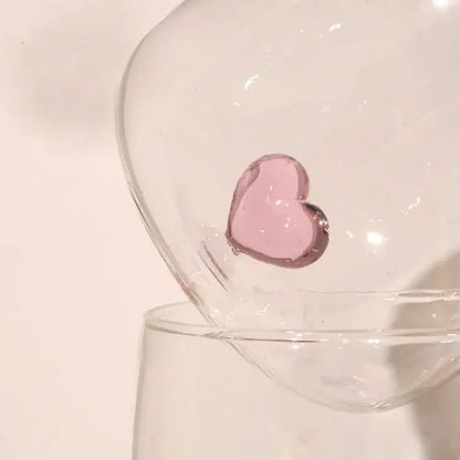 A translucent pink glass heart ornament inside a clear bowl complementing the decorbites 3d heart tumbler mug design