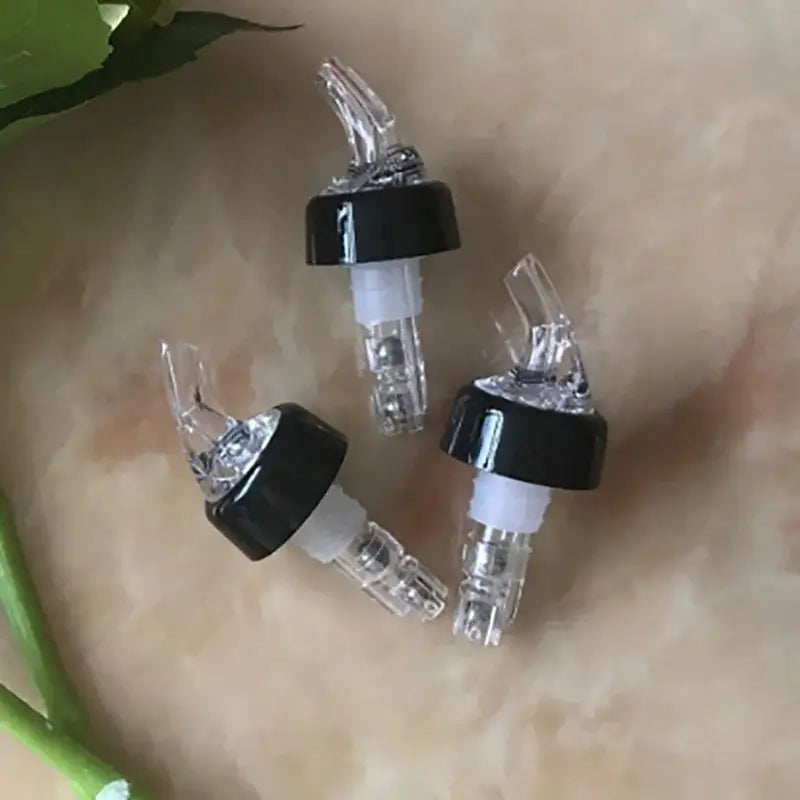 Three clear plastic decorbites liquor pourer bottle dispensers with black caps and white rubber seals for barware use