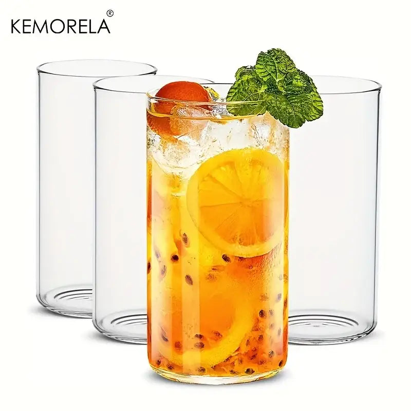 Clear borosilicate drinking glass filled with orange beverage garnished with lemon, mint, and passionfruit seeds from drinking glasses set