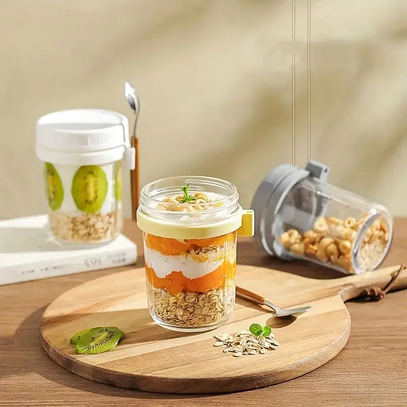 Clear borosilicate drinking glass jar with yellow lid and side handle filled with layered oatmeal parfait topped with kiwi slices