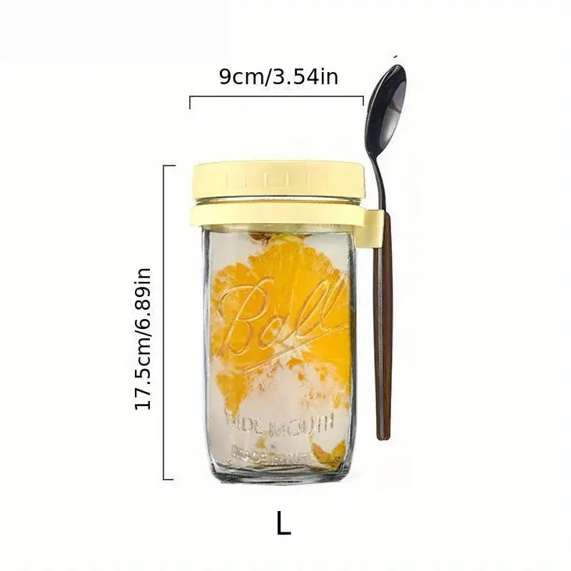Clear borosilicate drinking glass ball mason jar with pale yellow lid and spoon holder containing orange slices