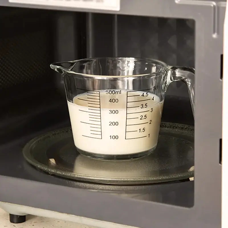 Clear borosilicate glass measuring cup with black markings and handles containing white liquid by decorbites borosilicate glass