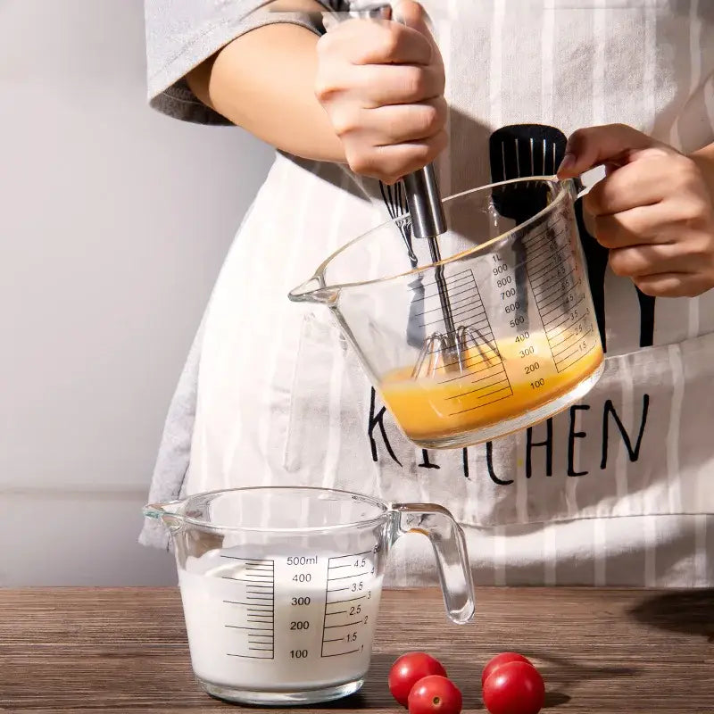 Clear borosilicate glass measuring cup with black markings and handle filled with orange liquid by decorbites borosilicate glass