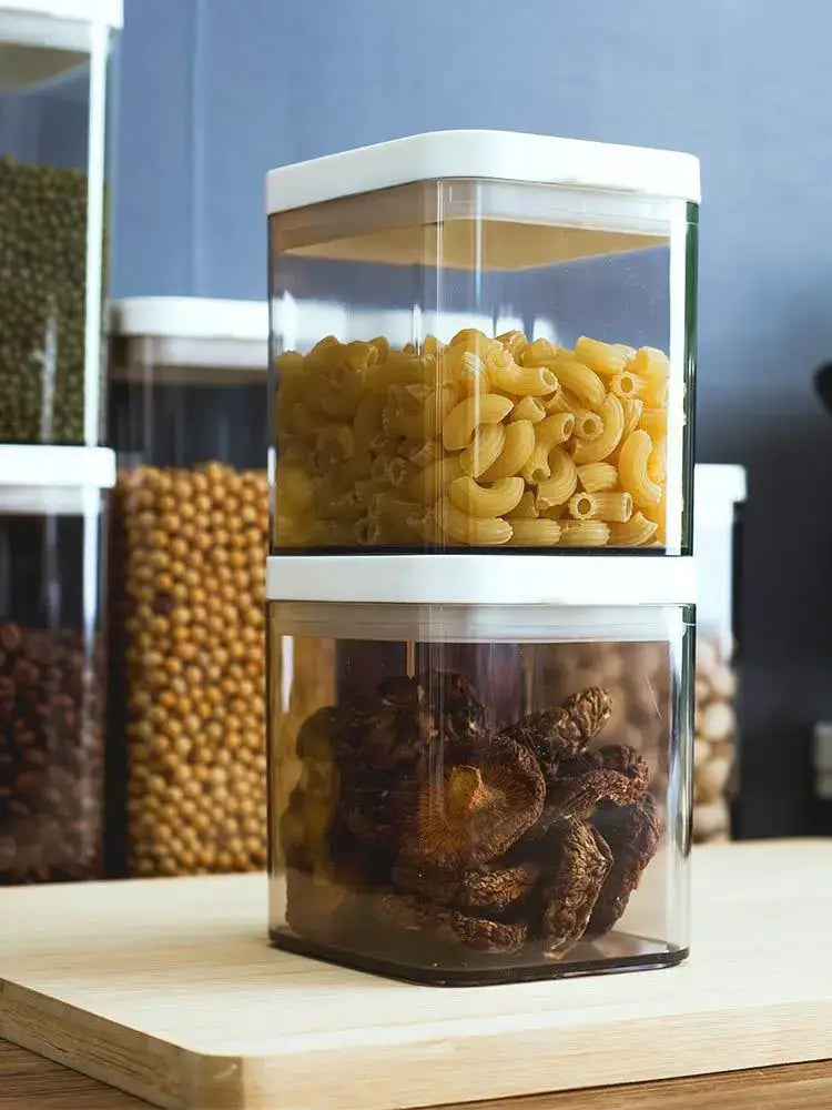Clear bulk hermetic food storage container with white lid filled with yellow macaroni and dark dried mushrooms
