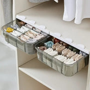 Clear divided plastic drawer closet organizer with white clips and compartments holding neatly folded colorful socks
