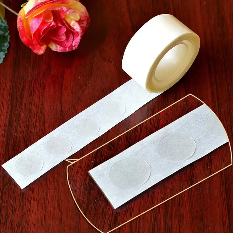 A roll of clear adhesive dots on white backing for use in clear embossed plastic balloon arch garland kit party decor