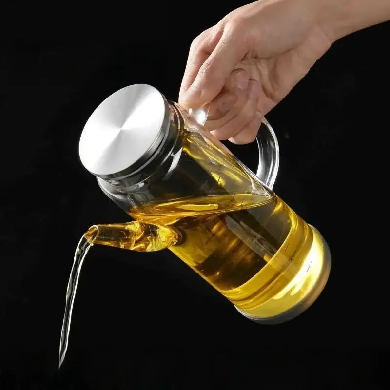 Clear glass and silver condiment bottle set featuring a glass oil dispenser filled with golden-yellow cooking oil