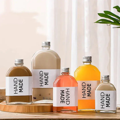 Clear glass beverage bottles with silver caps and hand made labels filled with colorful liquids for kitchen juicing set
