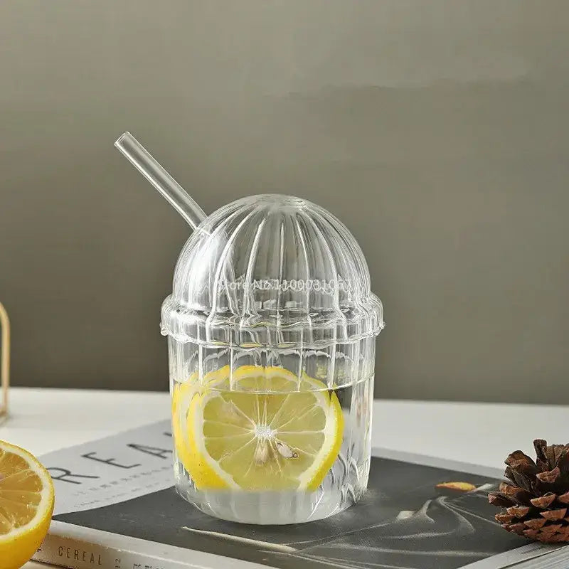 Clear glass bobo cup with ribbed dome-shaped lid and straw filled with lemon water from decorbites clear glass set