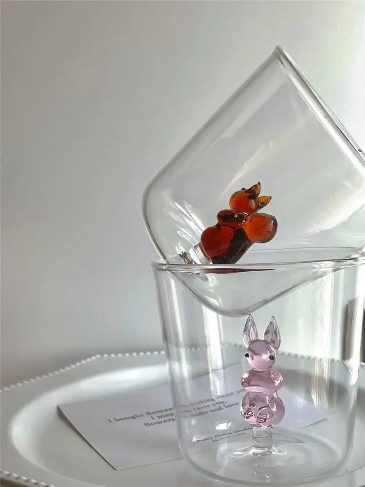 A translucent pink glass cactus bunny figurine with black bead eyes inside a clear glass cup decorbites cactus bunny