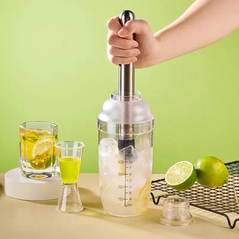 Transparent plastic cocktail shaker with stainless steel lid and handle filled with ice and citrus juice for decorbites beverage mixer