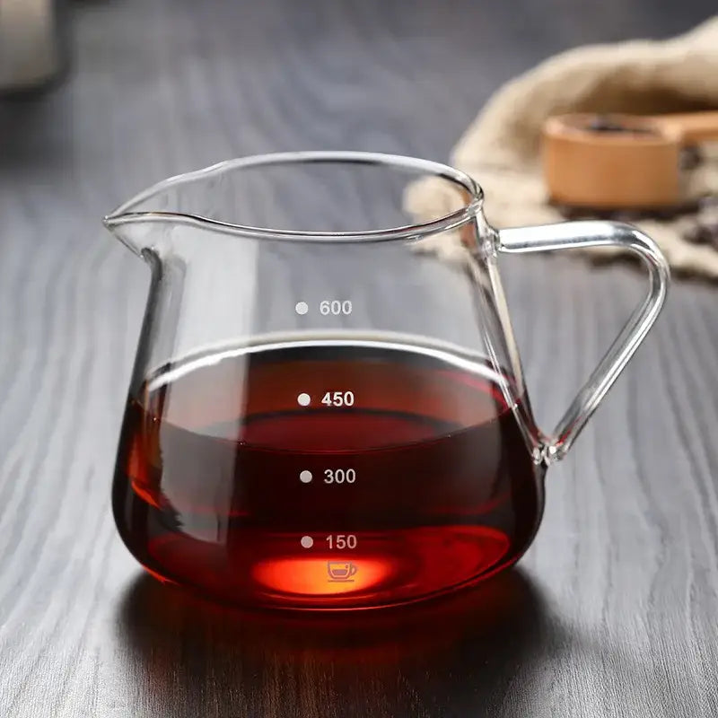 Clear glass coffee pot with measurement markings and handle filled with dark red liquid for kitchen use