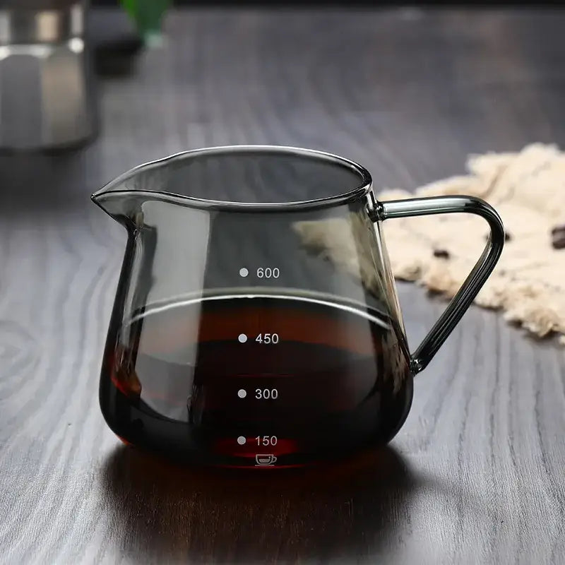 Clear glass coffee pot with black handle and milliliter measurement markings for precise kitchen use