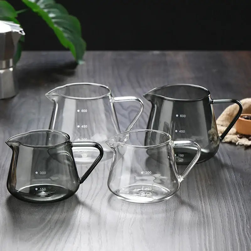 Set of four clear glass coffee pots with black handles and measurement markings in milliliters for kitchen use