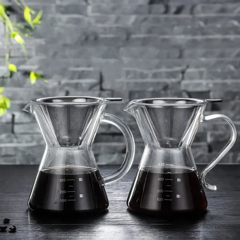 Two clear glass coffee pots with stainless steel filter and measurement markings filled with brewed coffee