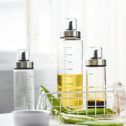 Clear glass condiment bottle set with silver caps black pumps and milliliter measurements for kitchen use