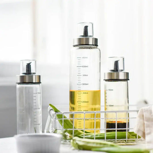 Clear glass condiment bottle set with silver caps black pumps and milliliter measurements for kitchen use