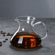 Clear glass drip pot coffee carafe filled with dark amber liquid from a kitchen pot coffee set with filter
