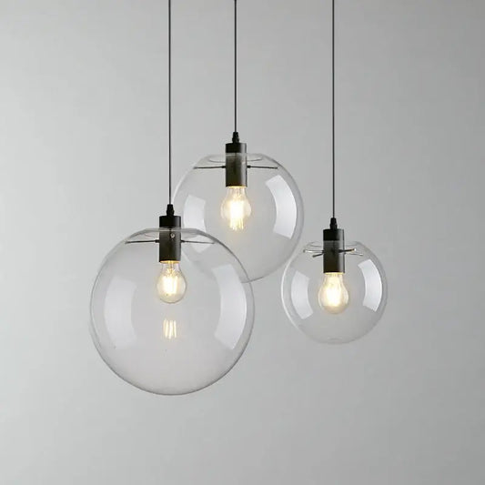 Clear glass globe pendant light with glass shade and black metal fixtures featuring exposed filament bulbs for kitchen cord pendant installation