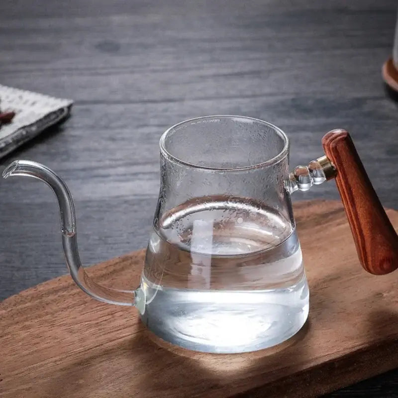 Clear glass hand drip coffee kettle with polished wooden handle and brass accents filled with water drip kettle decorbites glass coffee
