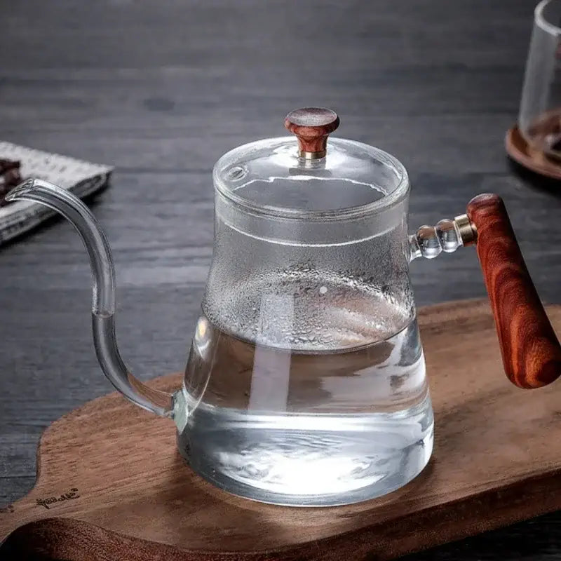 Clear glass hand drip coffee kettle with rich brown wooden handle and lid knob featuring a sleek curved spout drip kettle decorbites glass coffee