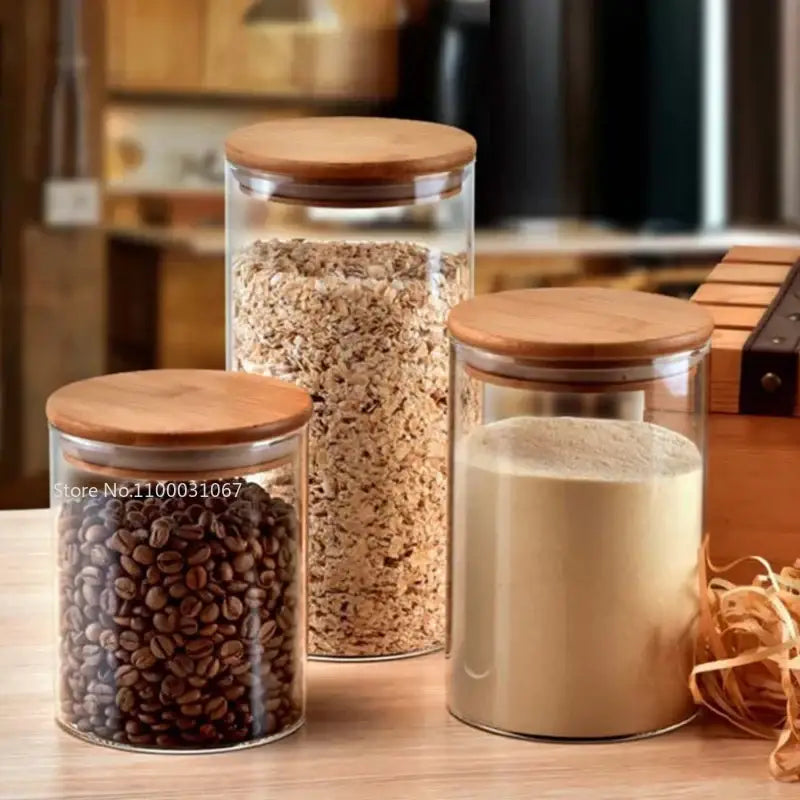 Three clear glass storage jars with bamboo lids holding dry goods for kitchen organization and glass storage