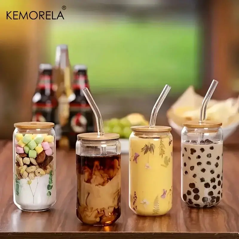 Clear glass tumbler cups with bamboo lids and curved glass straws featuring colorful marshmallows and boba tea