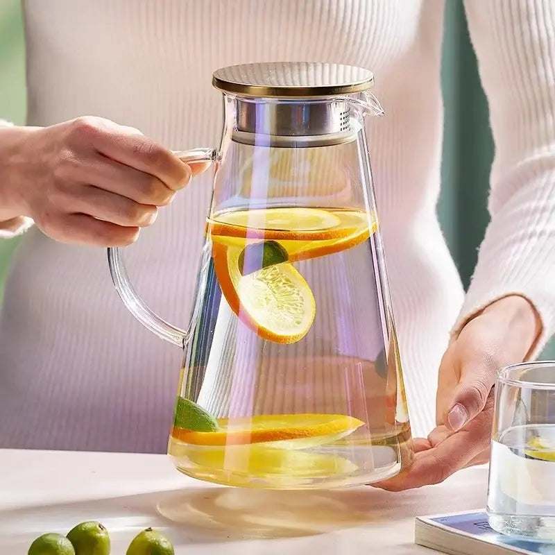 Clear gold glass juice kettle set with citrus-infused water in a glass juice kettle with gold-toned lid and handle