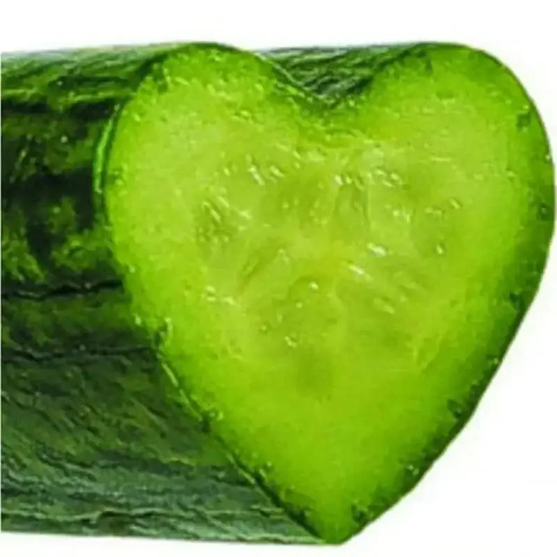 A clear heart shaped vegetable growth mold creating a vibrant green cucumber slice with visible seeds and moist texture