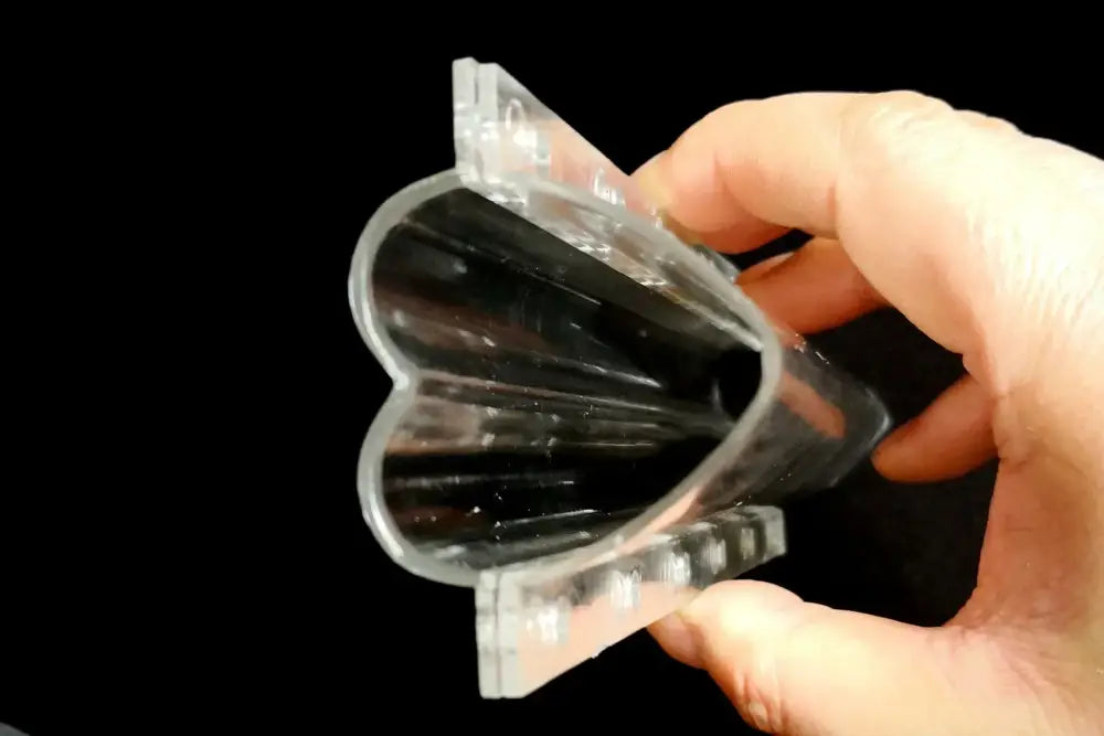 Clear plastic heart shaped vegetable growth mold with fluted segmented interior and ridged edges for cucumber growth