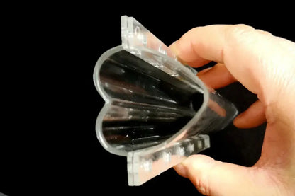 Clear plastic heart shaped vegetable growth mold with fluted segmented interior and ridged edges for cucumber growth