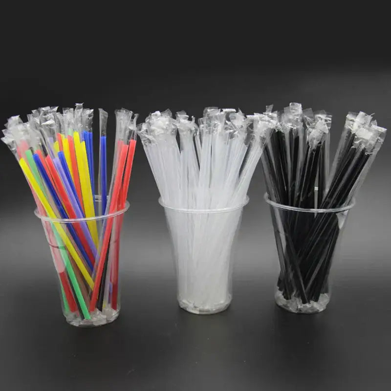 Three clear plastic cups hold decorbites clear individually wrapped drinking straws in multicolor white and black