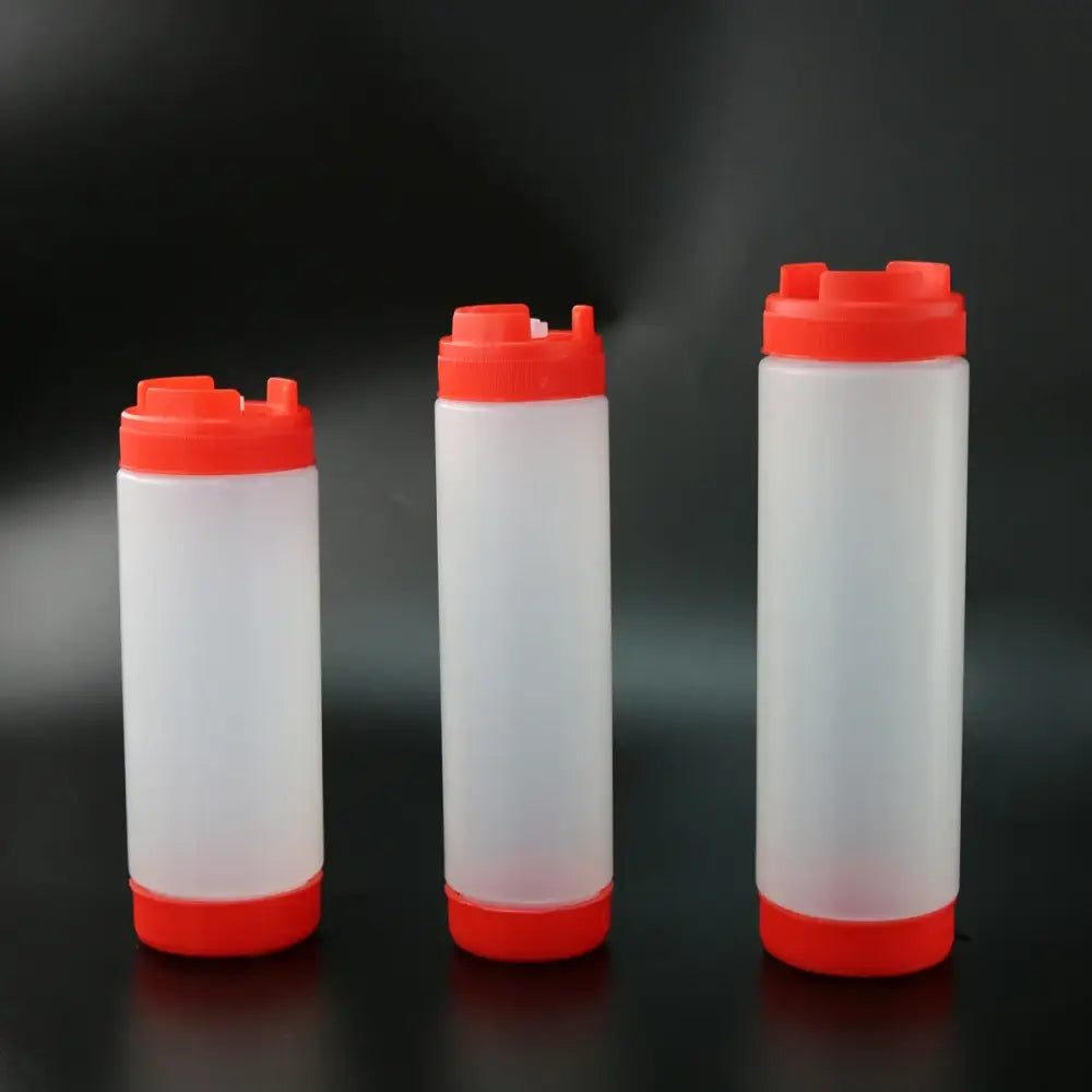 Three translucent white plastic tomato squeeze bottles with bright red caps and bases arranged in a row