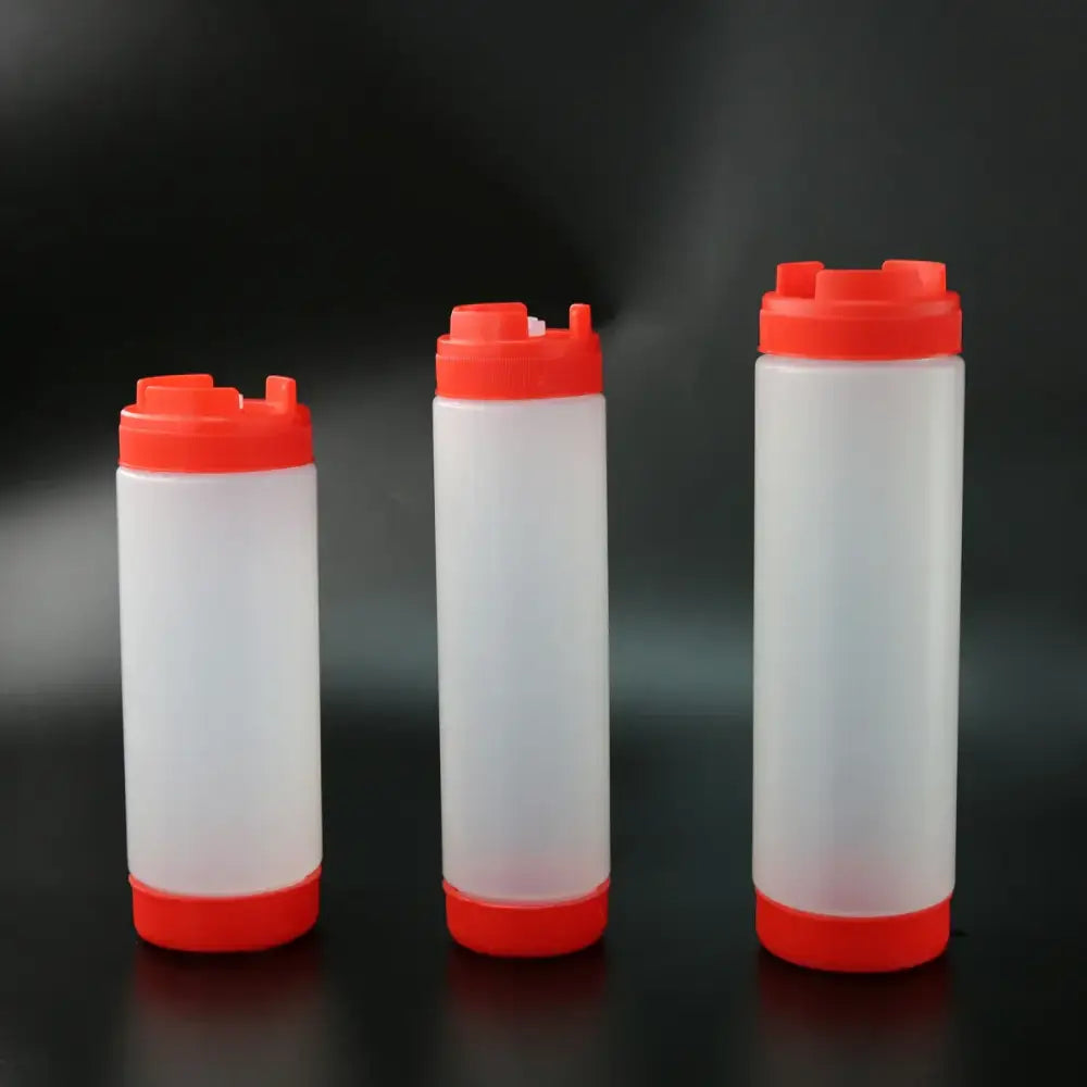 Three translucent white plastic tomato squeeze bottles with bright red caps and bases arranged in a row