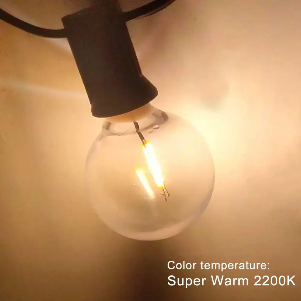 A glowing clear shatterproof g40 1w pet led bulb with black base emitting warm 2200k light for outdoor string lights