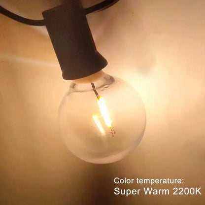 A glowing clear shatterproof g40 1w pet led bulb with black base emitting warm 2200k light for outdoor string lights
