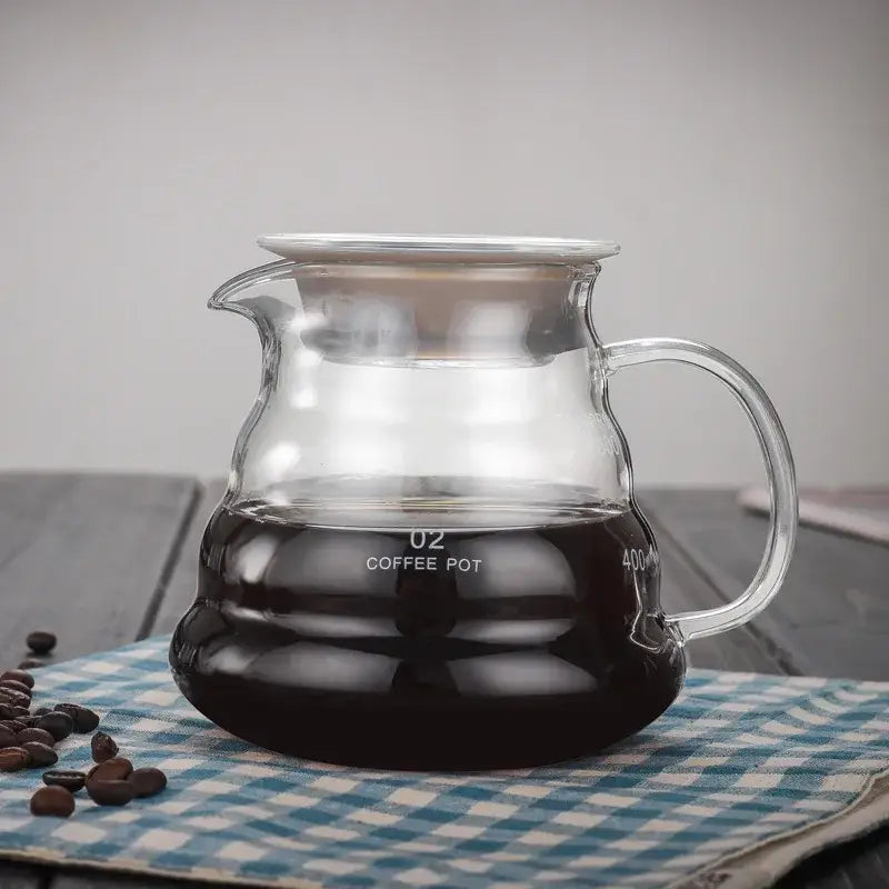 Clear glass cloud shaped glass coffee kettle with silver lid and handle filled with dark brewed coffee by decorbites