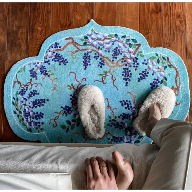 Cloud shaped teal door mat with purple wisteria embroidery and scalloped edge featuring soft white slippers decorbites grape vine