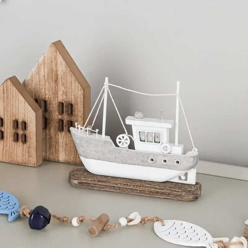 White and gray painted wooden ship model with distressed finish resting on driftwood for decorbites coastal wooden decor