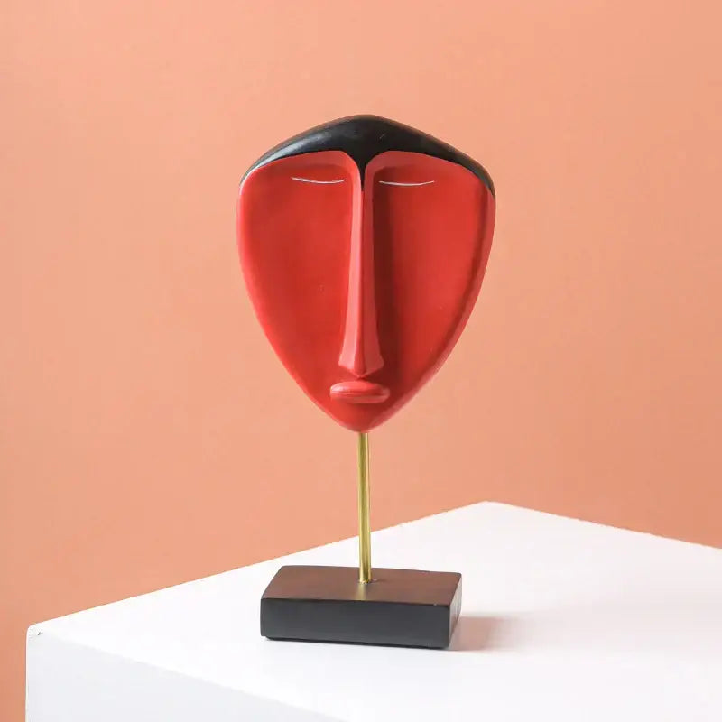 A sleek colorful african abstract face monkey sculpture in red with black top on gold stand for living room decorbites decor