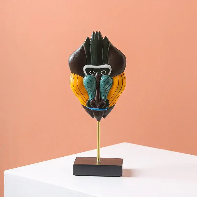 Vibrant hand-painted african abstract face monkey sculpture with black yellow teal accents on gold stand for living room decorbites african abstract decor